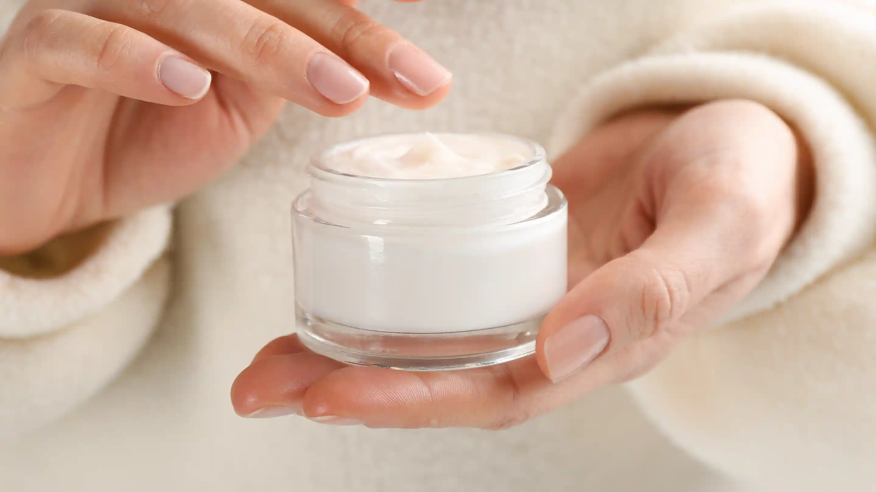 Woman scooping cream from a clear container