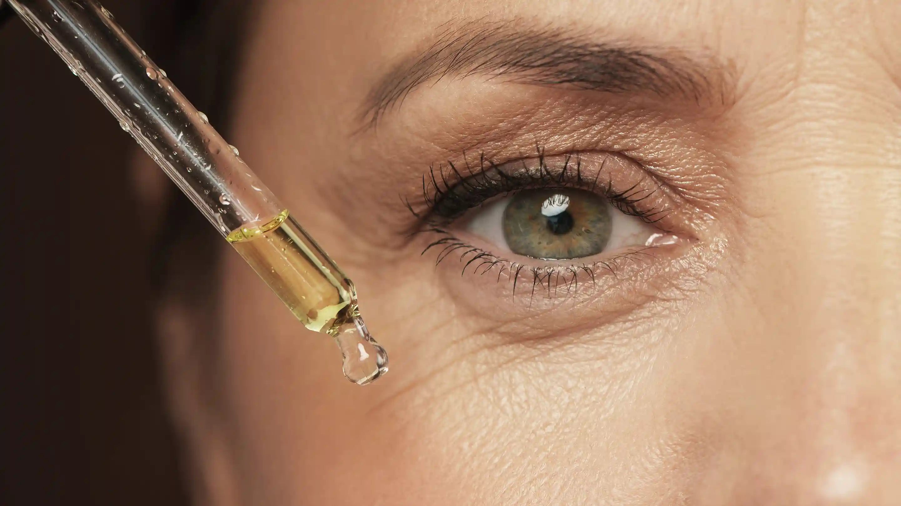 Woman dropping face serum near her eye