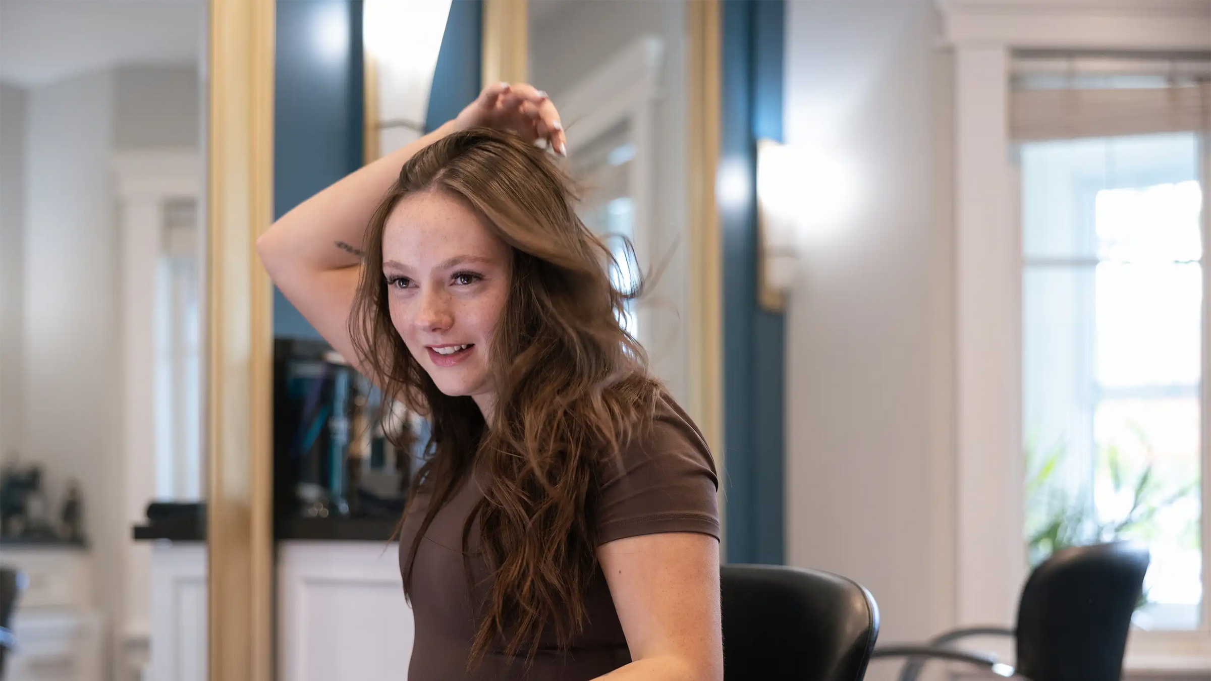 Women smiling as she runs her hands through her freshly styled hair