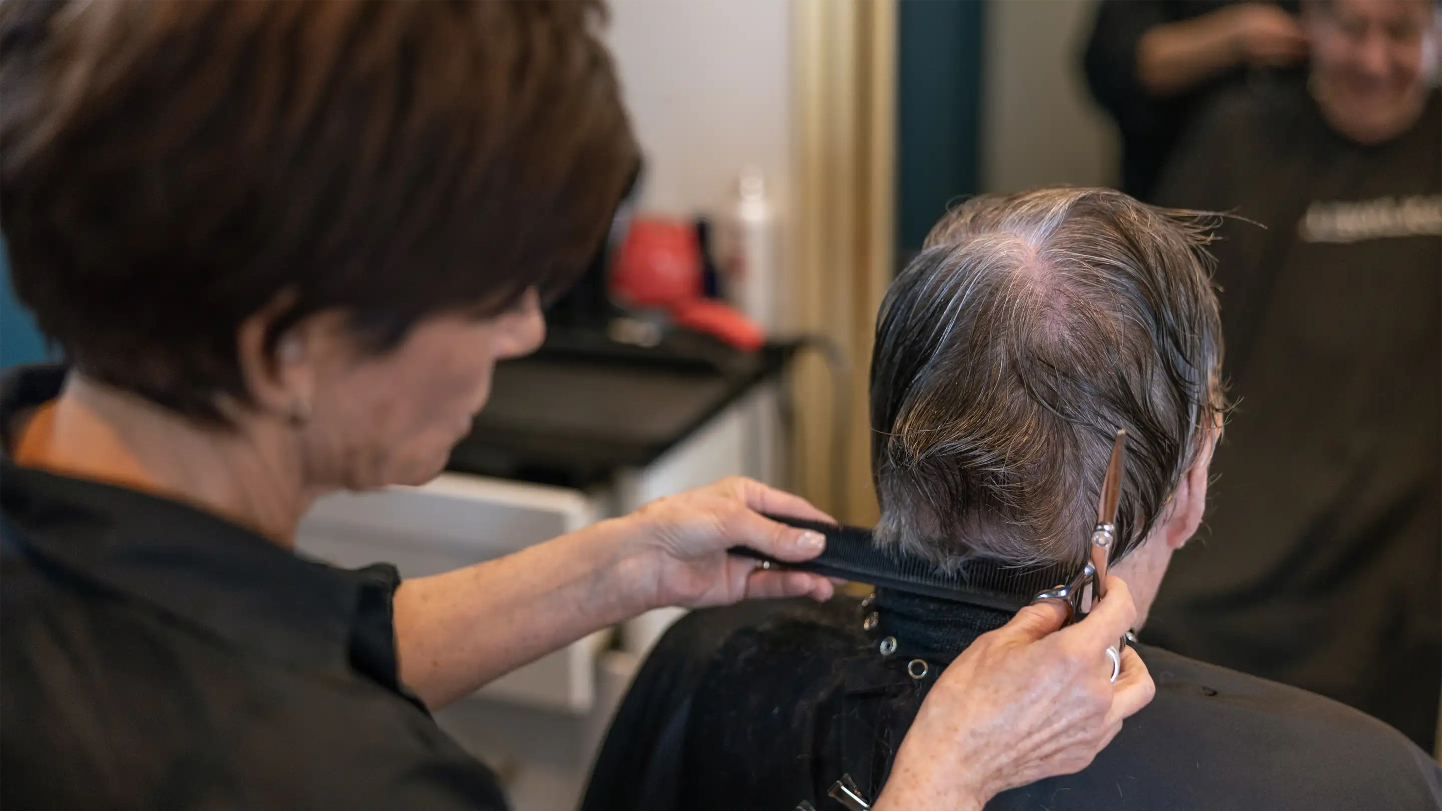 Woman cutting a man's hair from behind