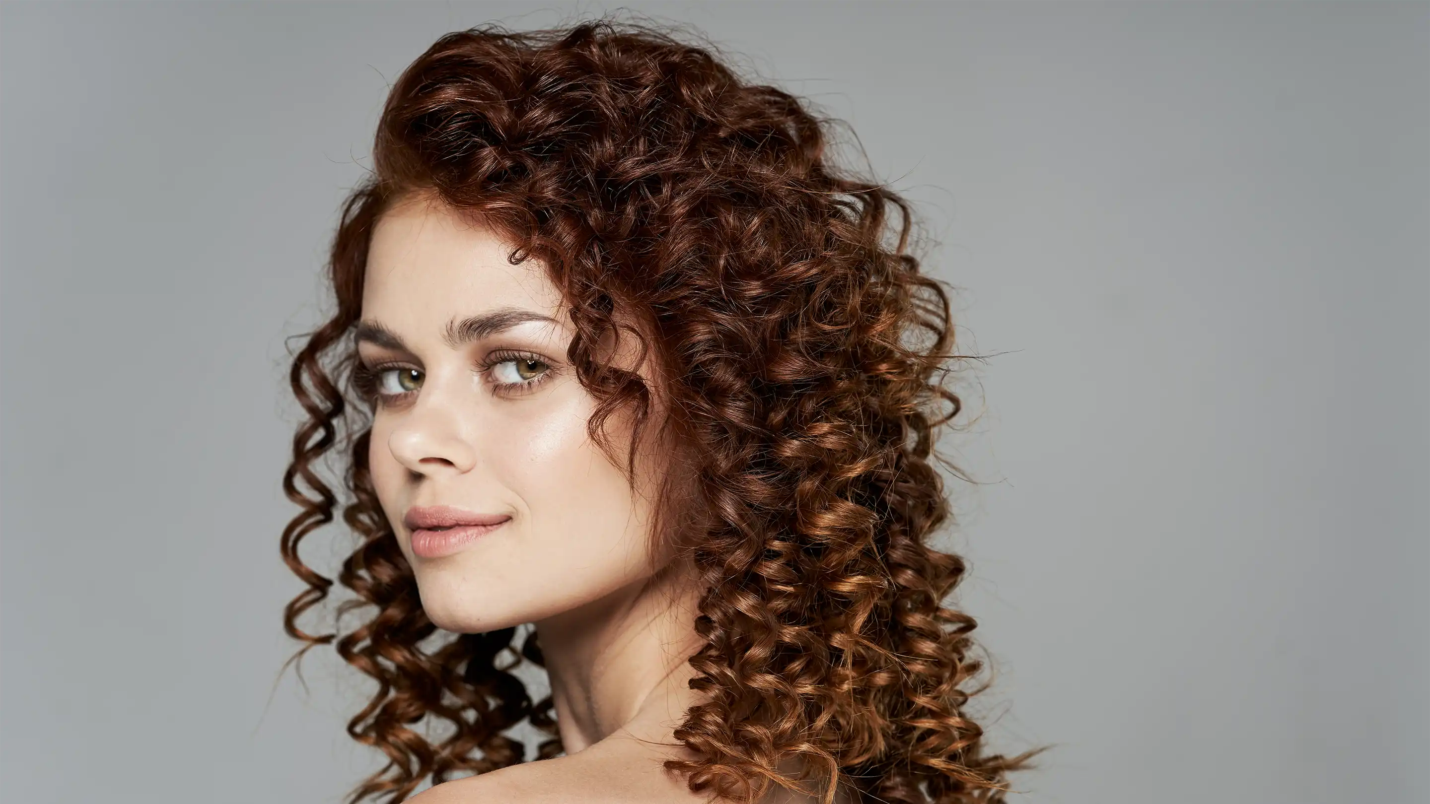 A woman smiling showing off her perm hair style