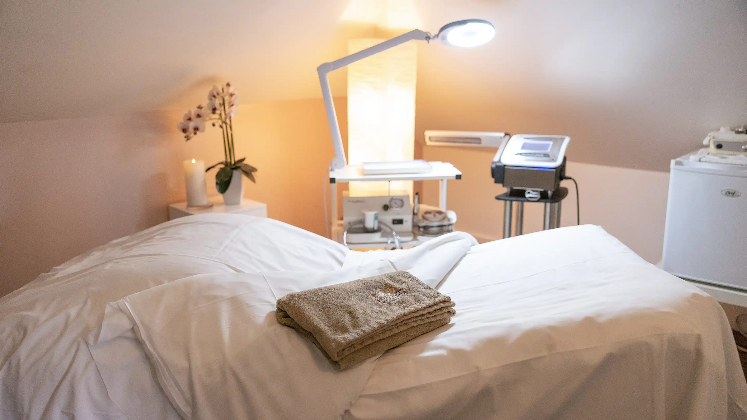 Neatly folded towel on a bed in a serene room for facial treatments